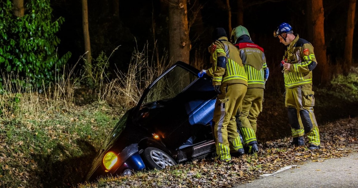 Brandweer moet bestuurder uit zijn auto bevrijden in Enschede, nadat hij met voertuig in sloot belan