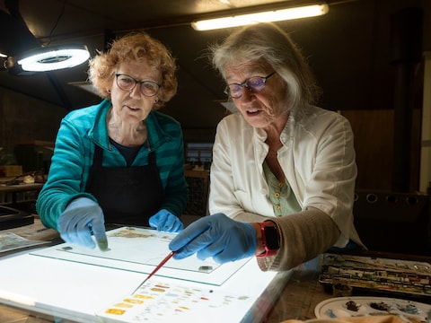 Glazenier Betty Bulthuis en verfspecialist Jitske Rinsma tijdens de restauratie van het historisch glaspanorama, te zien tijdens Glasrijk Tubbergen. 